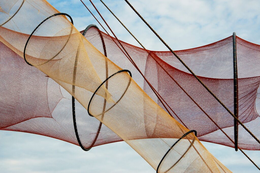 Colorful fishing nets create an abstract pattern against a bright blue sky.